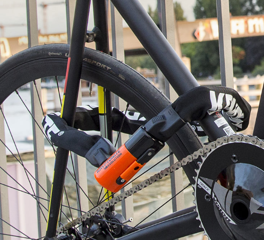 Paksu musta ketjulukko kiinnitettynä polkupyörän rungon ja takapyörän ympäri.